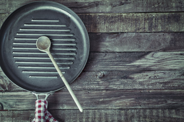 黑色的烤盘放在棕色的木头表面上图片下载