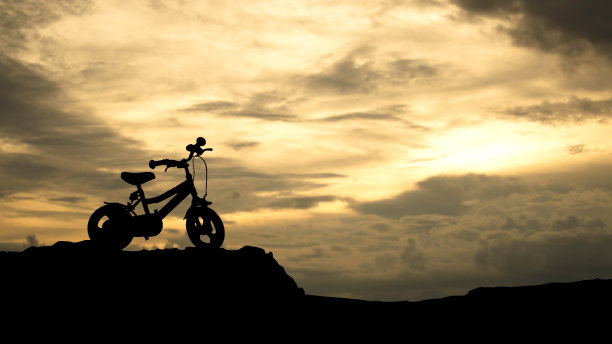 一辆儿童自行车的剪影在一个彩色的日落图片下载