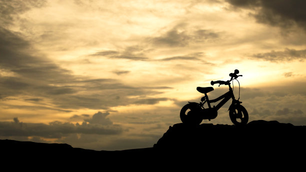 一辆儿童自行车的剪影在一个彩色的日落图片下载