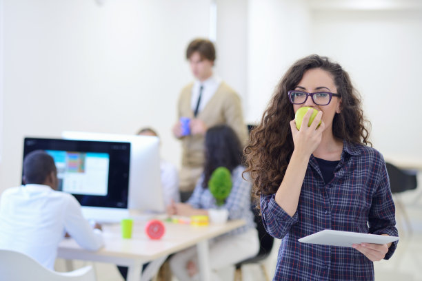 一个年轻漂亮的女人拿着平板吃苹果的照片图片下载