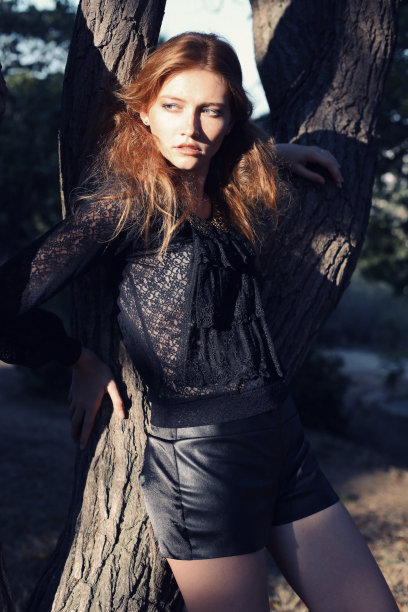 红发雀斑女孩在树旁摆姿势图片下载