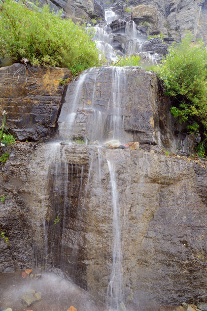 平滑的瀑布穿过冰川的绿色植物。图片下载