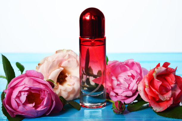 蓝色木桌上带鲜花的粉色香水瓶图片下载
