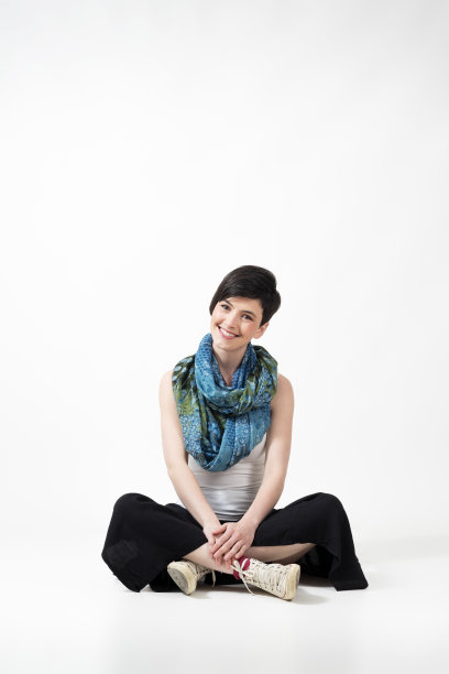 可爱的女人坐在交叉的腿和微笑的镜头图片下载