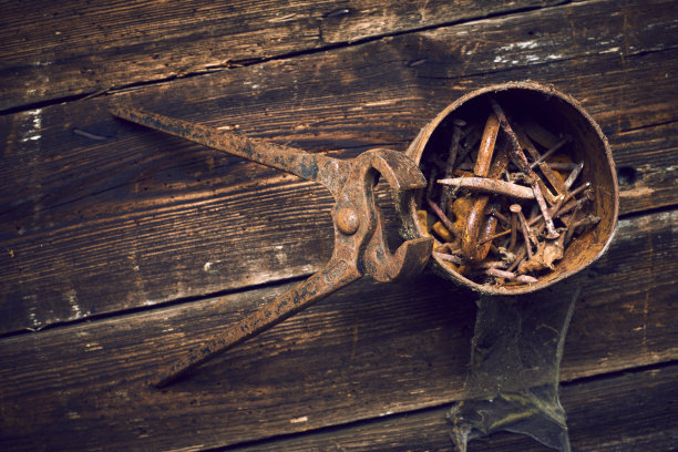 在木板上用生锈的老钳子夹着一罐钉子图片下载