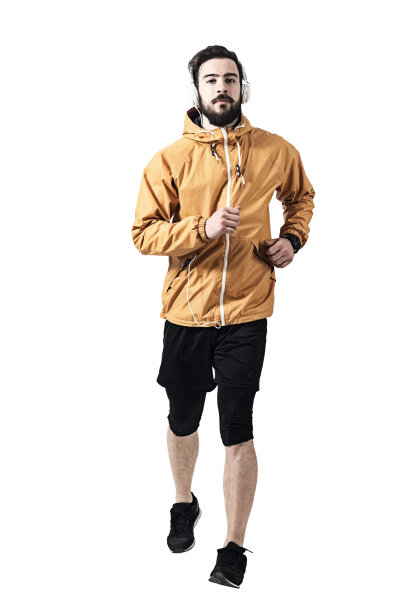 坚定的年轻慢跑者穿着夹克戴着耳机跑向相机图片下载