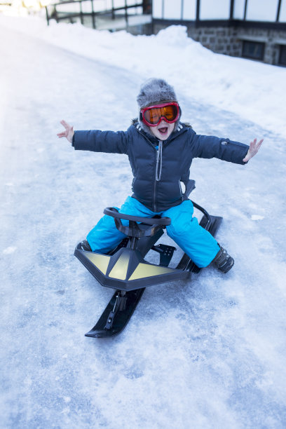 快乐的小孩在他的雪地摩托上玩得很开心。图片下载