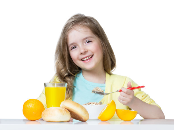 小女孩在餐桌上独自吃饭。素材图片