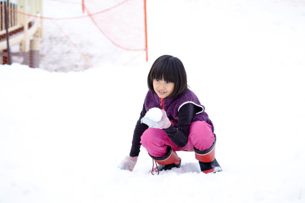 亚洲女孩在雪公园玩雪球图片下载