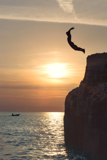 男孩从悬崖上跳下来，飞向天空素材图片
