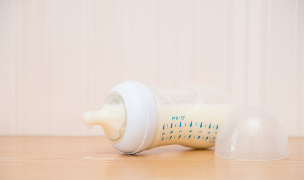 婴儿奶瓶和牛奶放在一张木桌上图片下载