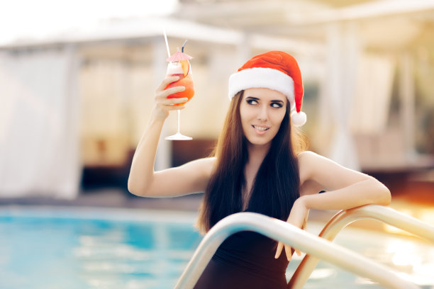 在泳池边喝着鸡尾酒的性感圣诞女人图片下载