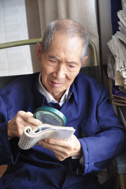 年长的中国男子正在用放大镜看书图片下载