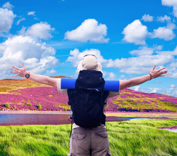 一个背着黑色背包的徒步旅行者张开双手，表达快乐图片下载