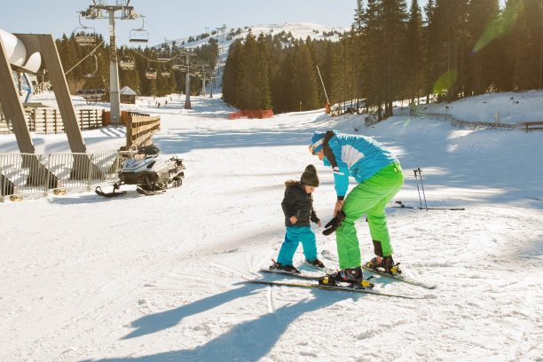 小孩子跟着滑雪教练学滑雪。图片下载