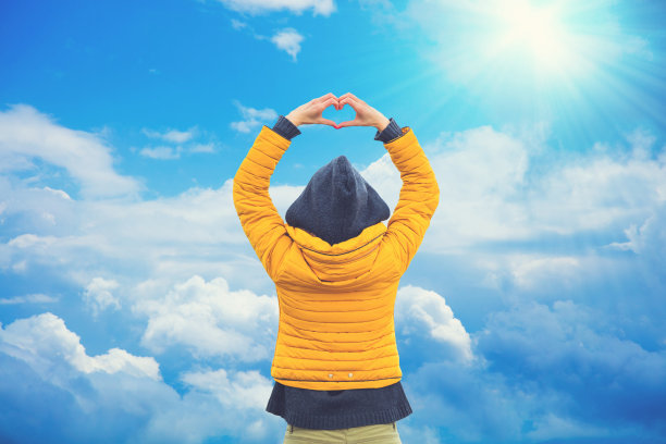 女孩为美丽的天空和太阳做了一个心形。图片下载