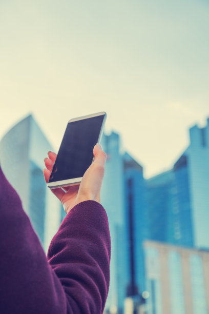 都市女孩，手机和摩天大楼的背景。图片下载