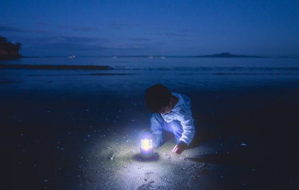 孩子们拿着灯笼在沙地上寻找。图片下载