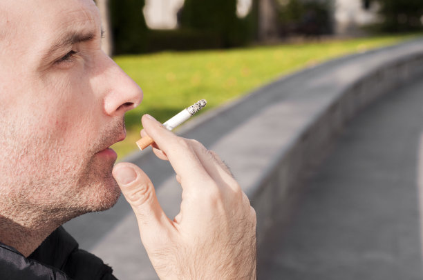 英俊潇洒的年轻人在城市的环境中吸烟图片下载