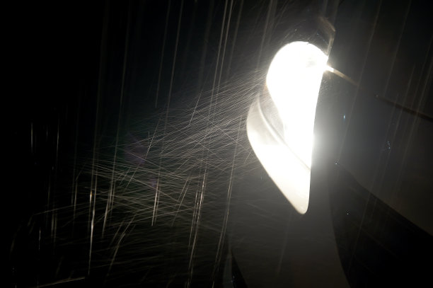 在黑暗中，雨影响了小轿车的前灯图片下载