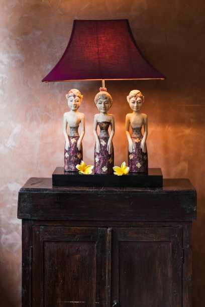 床头柜上的古董灯，上面有树巴厘小雕像图片下载