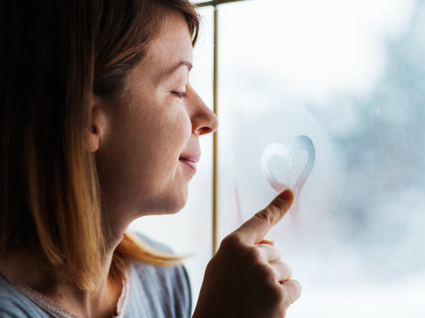 一个年轻女子在窗户上画了一颗心图片下载