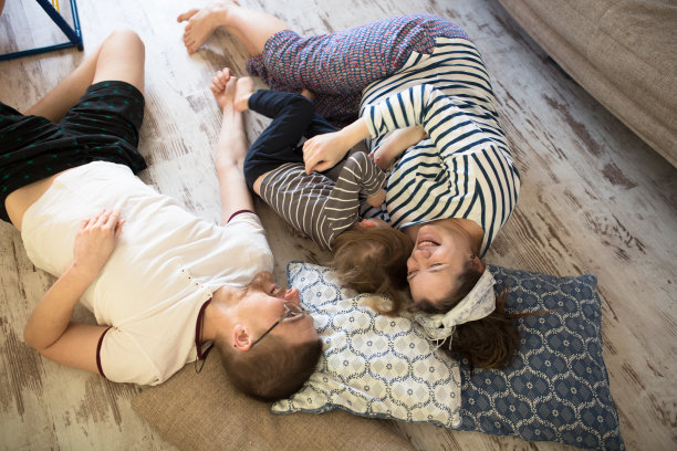 快乐的怀孕母亲，父亲和儿子学步躺在地板上图片下载