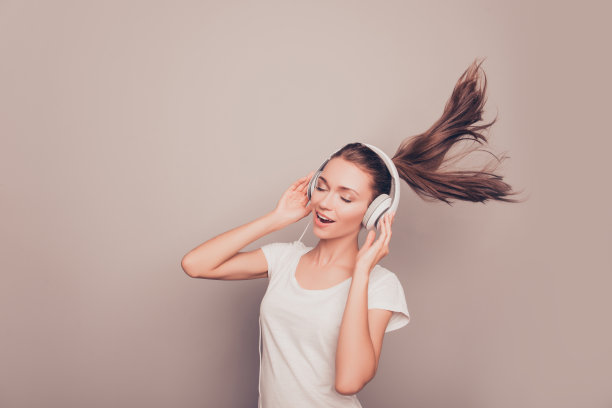 快乐微笑的女孩戴着耳机听音乐唱歌图片下载