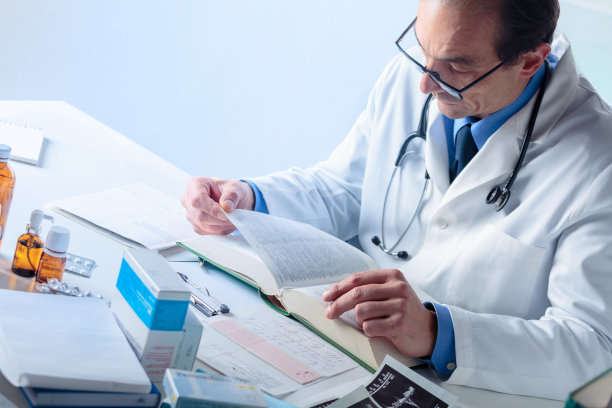 高级男医生在医学书籍中寻找信息图片下载