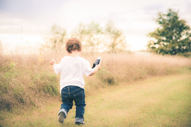 小男孩穿着一只鞋在田野里奔跑图片下载