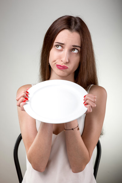 年轻女子展示空盘子。图片下载