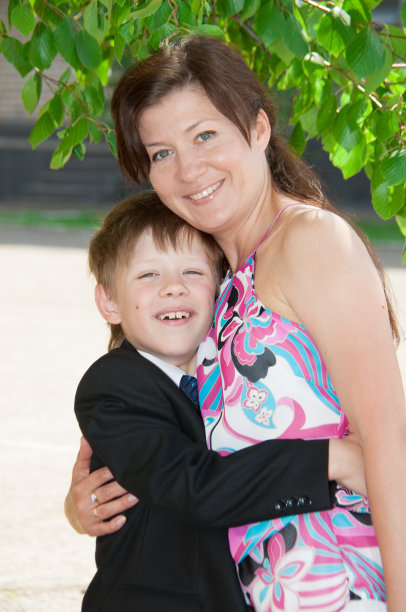 男孩和他的妈妈站在树叶下图片下载