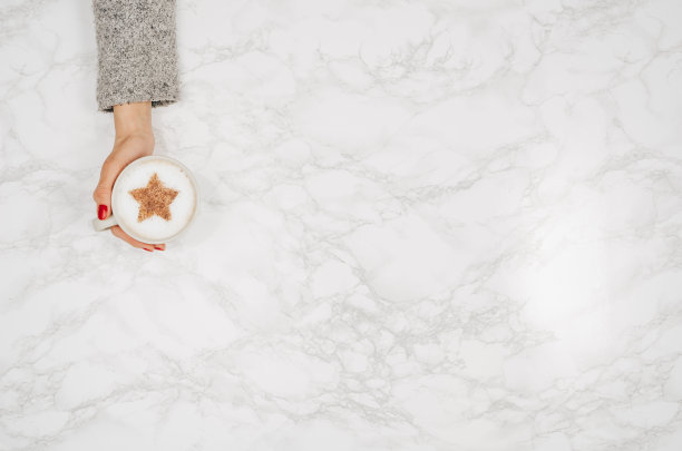 女人双手捧着咖啡放在五颜六色的桌子上，俯视图素材图片