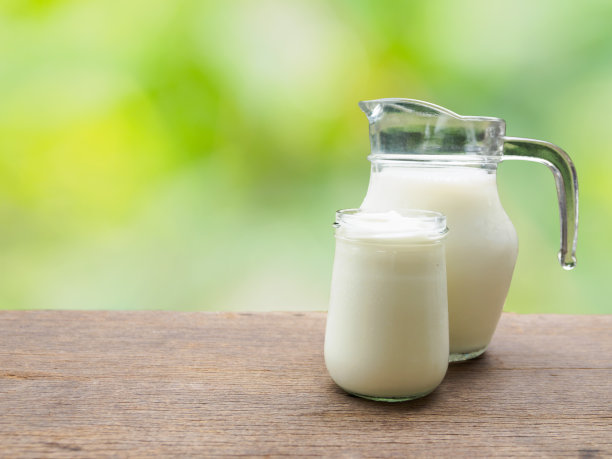 木桌上有牛奶罐和玻璃杯里的酸奶图片下载