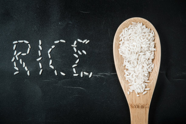 木勺里的米在黑色的背景上。图片下载