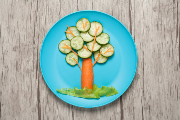 用黄瓜和胡萝卜做成的树，放在盘子和桌子上图片下载