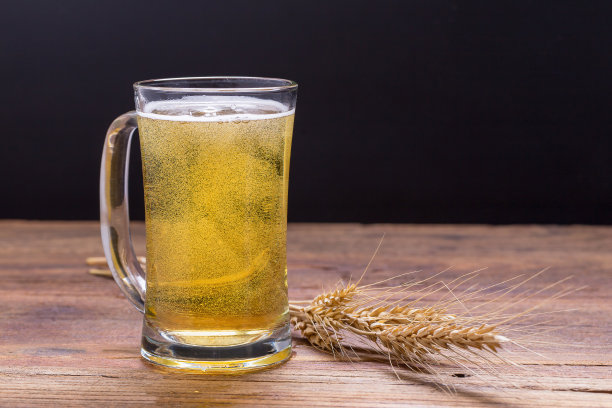 木桌上放着一杯啤酒。图片下载