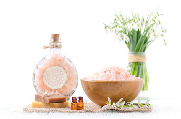 两瓶有机精油与新鲜的雪花莲花，肥皂，喜马拉雅盐在旧木制和白色的背景图片下载