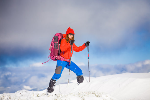 背着背包的女孩走在山上的雪地上。图片下载