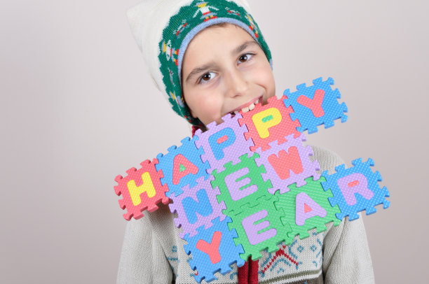 小男孩嘴里叼着一个新年快乐的标志图片下载