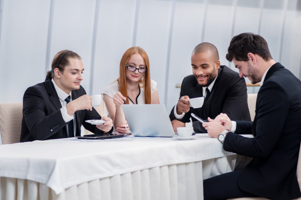 咖啡休息。四个微笑的成功商人坐在桌旁图片下载