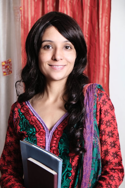 快乐的印度女孩与书摆姿势的室内肖像图片下载