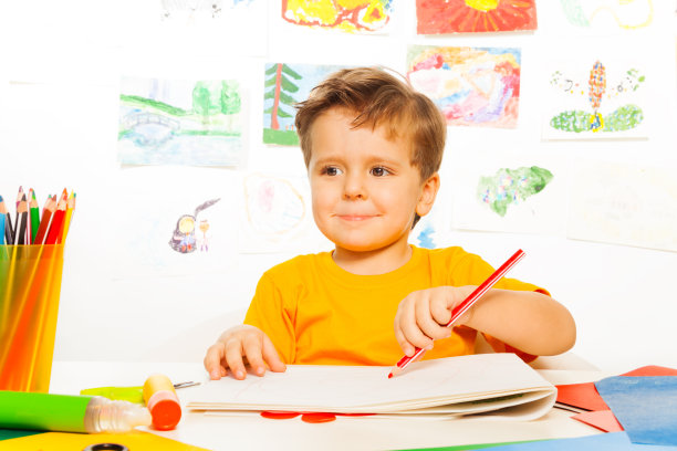 男孩在桌子上用铅笔在纸上画画图片下载