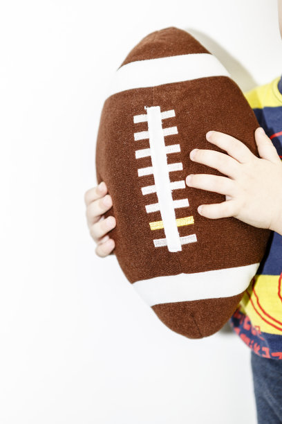 橄榄球玩具的孩子在男孩的手与白色的背景图片下载