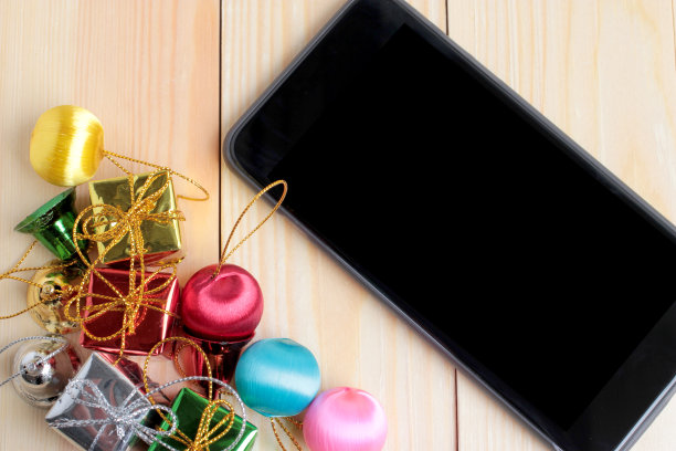 工作场所的智能手机和圣诞礼物装饰木质背景，图片下载