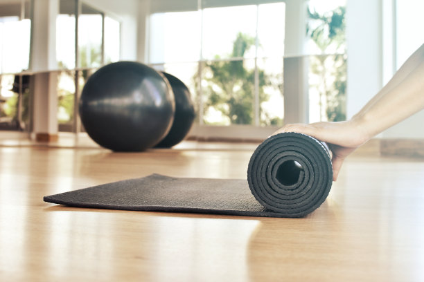 瑜伽课结束后，一个女人在滚动她的垫子图片下载