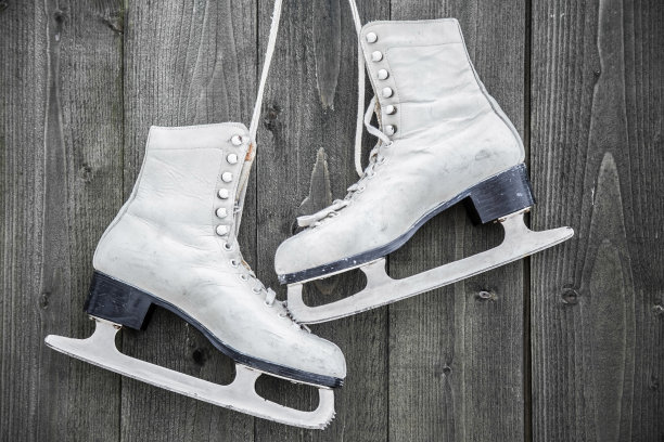 木墙上的白色旧溜冰鞋。周末户外活动。图片下载