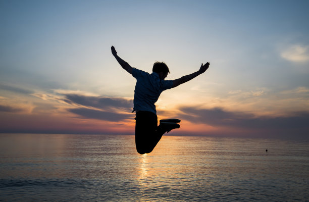 一个人影在暮色中的海滩上跳来跳去图片下载