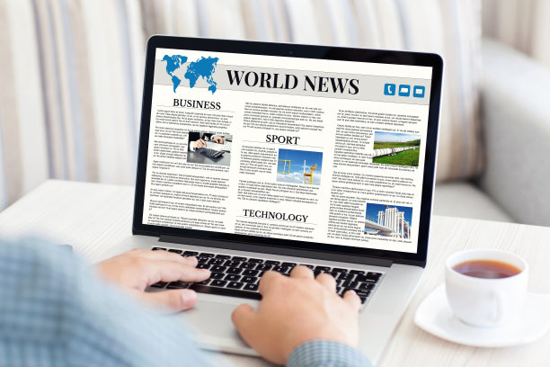一名男子拿着笔记本电脑，屏幕上显示着世界新闻网站图片下载
