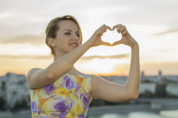 夕阳的天空用女人的手做成了心形图片下载